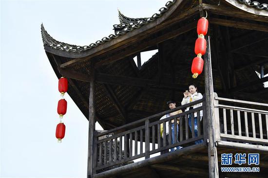  游客在重慶市武隆區(qū)黃鶯鄉(xiāng)復(fù)興村的觀景樓上欣賞田園景色（2019年3月28日攝）。 新華社記者 劉潺 攝